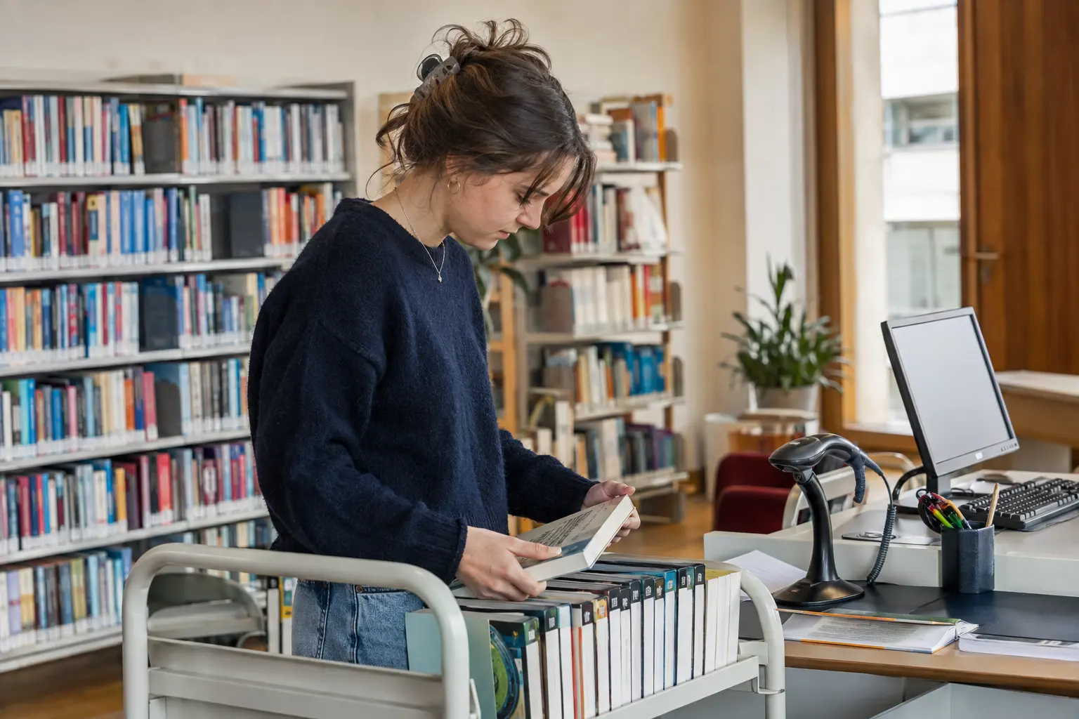 Bibliothekarin stellt Bücher im Regal ein