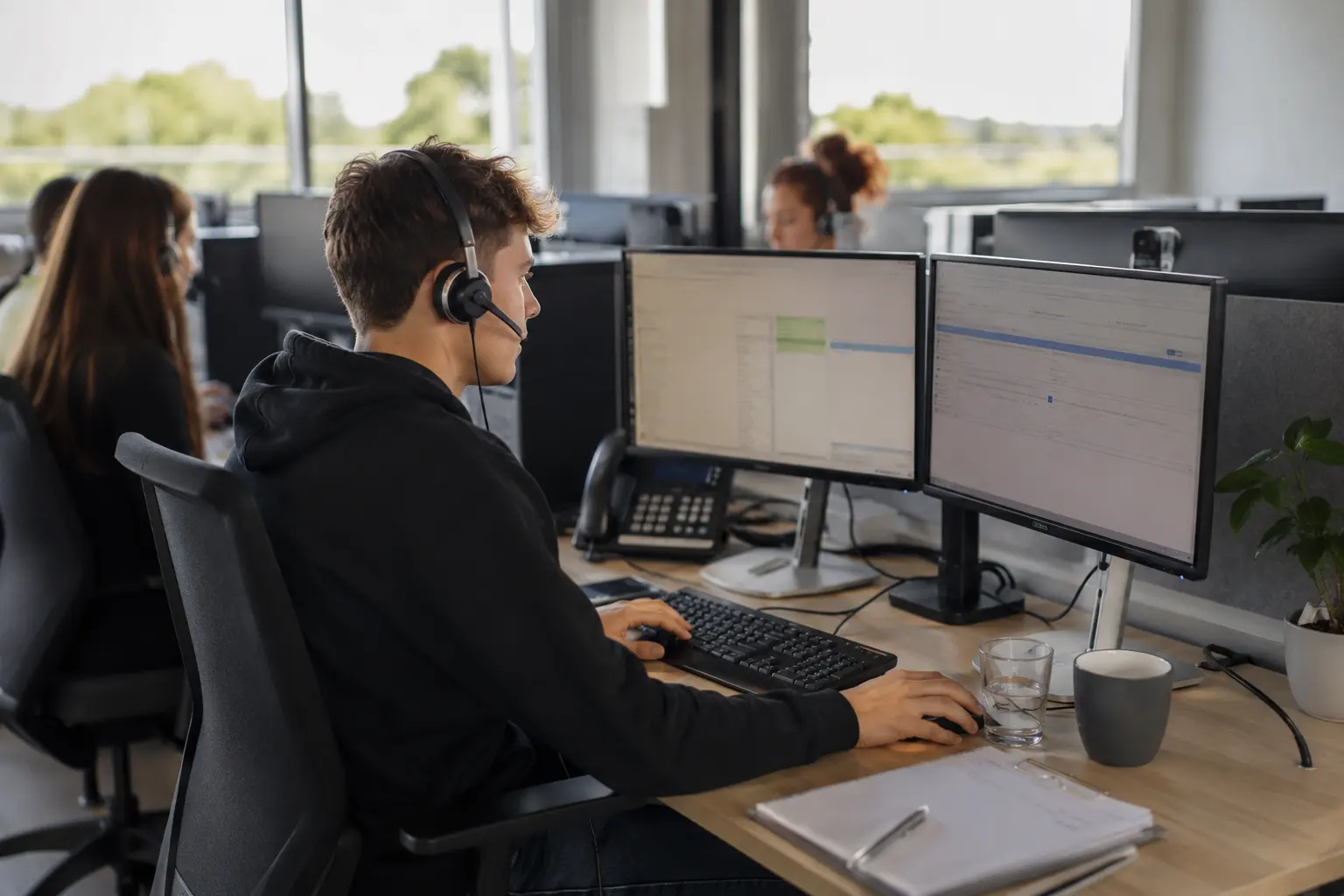 Call-Center-Agentin telefoniert mit Headset am Bildschirm