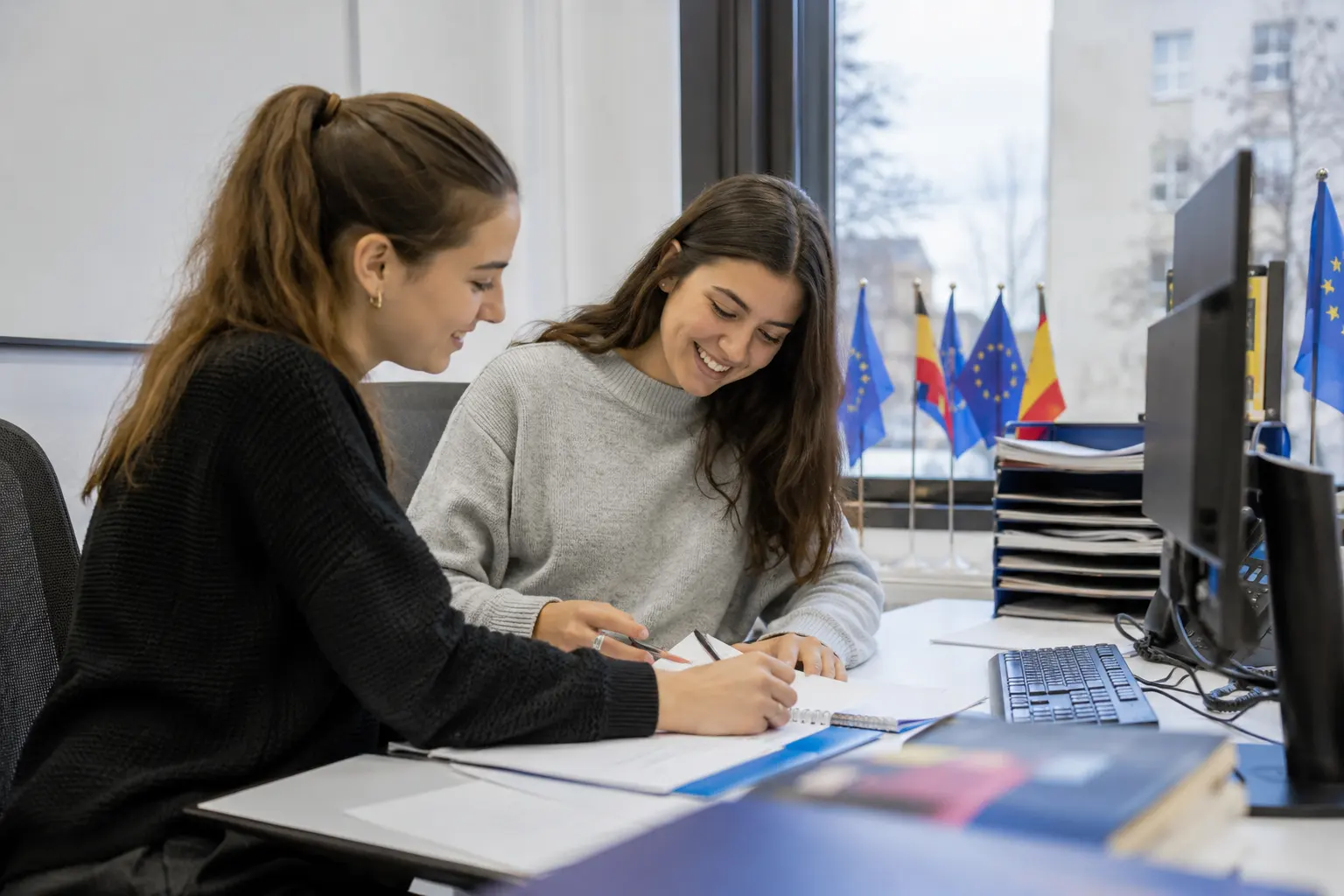Europa-Sekretärinnen arbeiten an Unterlagen, EU-Flaggen im Raum