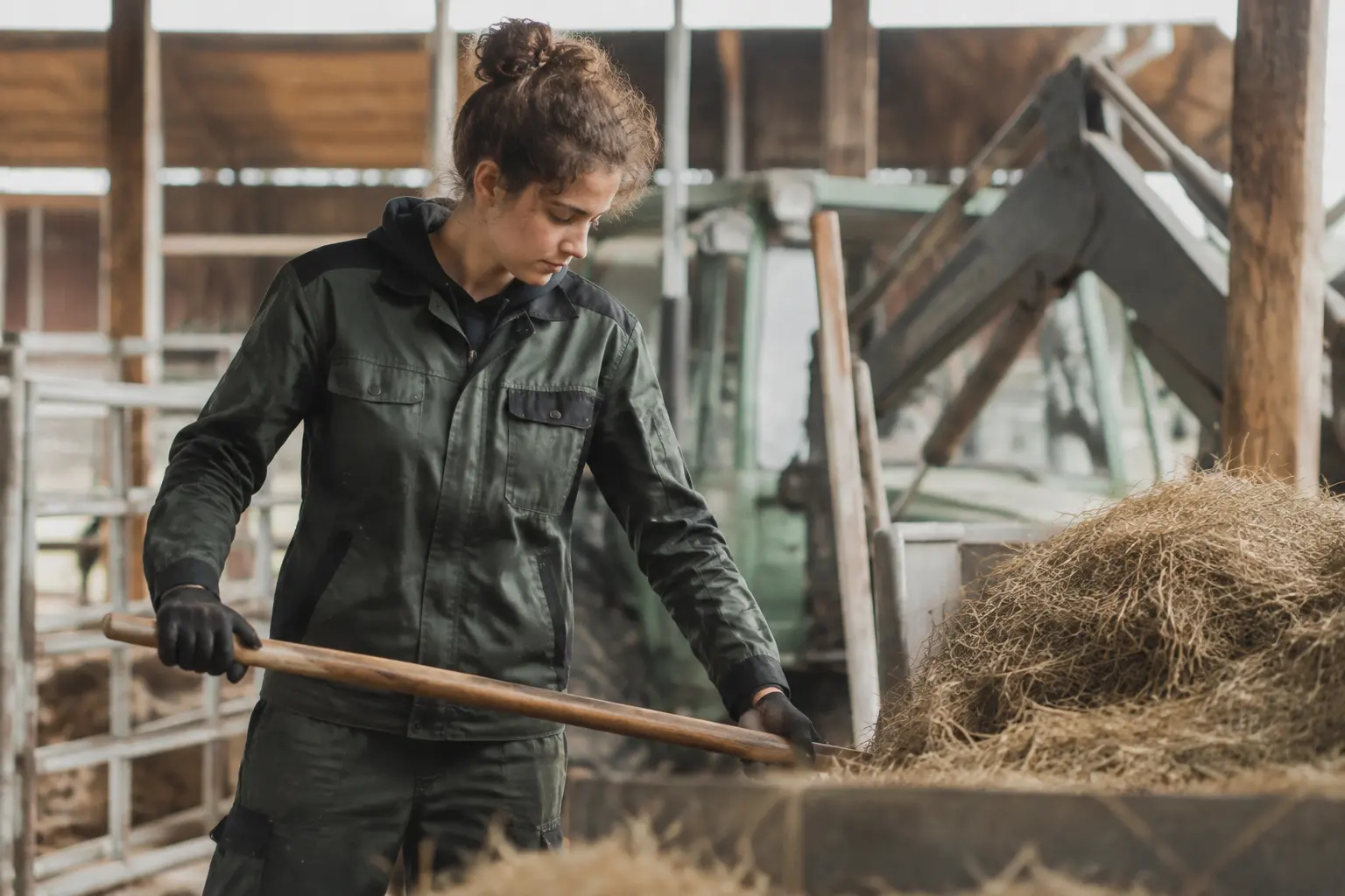 Landwirtin verteilt Stroh im Stall