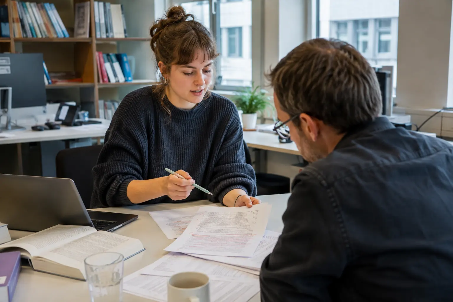 Lektorin bespricht ein korrigiertes Manuskript mit einem Autor
