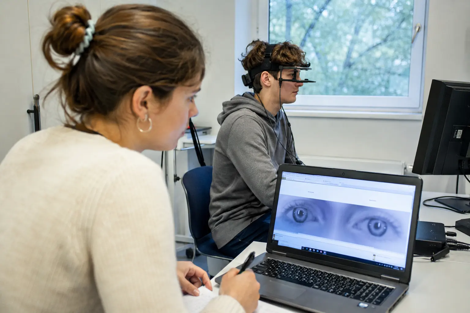 Studentin protokolliert einen Blickbewegungsversuch, Proband mit Eyetracker