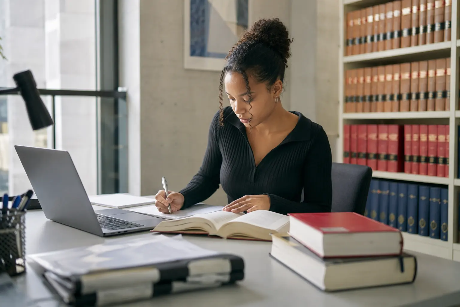 Studentin arbeitet mit Gesetzeskommentaren in der juristischen Bibliothek